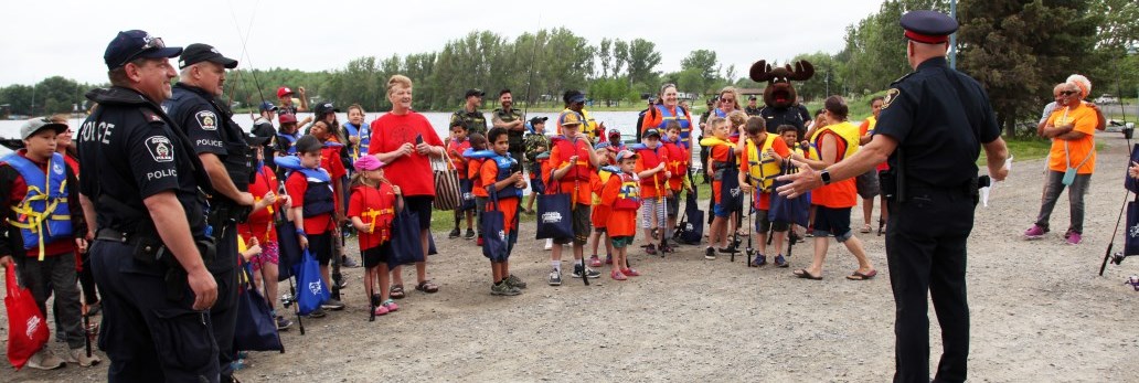 Chief of police talking to large group of children wearing life jackets