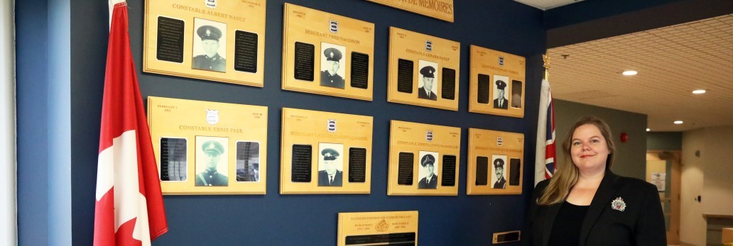 woman standing next to wall of memories with photos of fallen officers