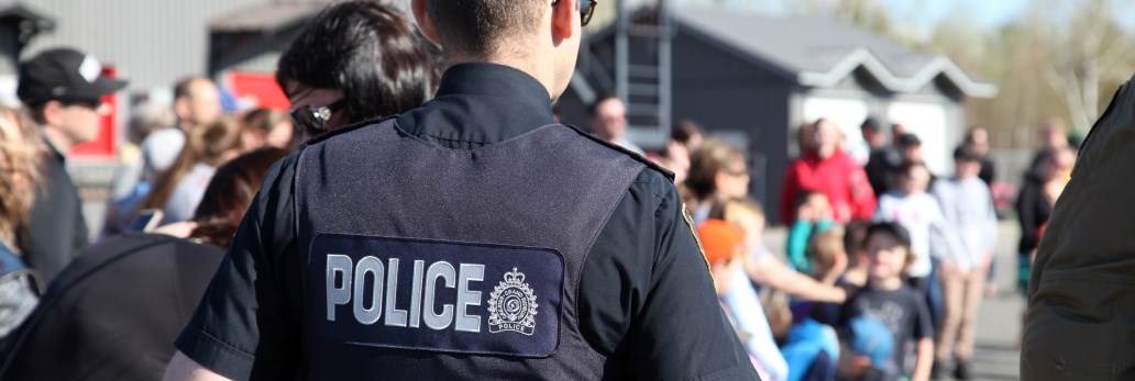 view of Police officer's back looking toward group of blurred people