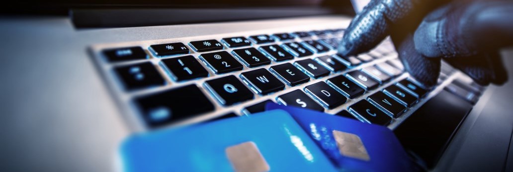 gloved hand typing on keyboard next to credit cards