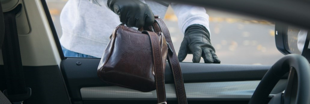 gloved thief stealing purse from vehicle
