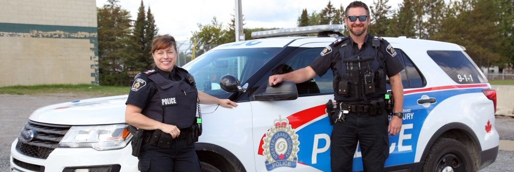 two officers standing beside police cruiser