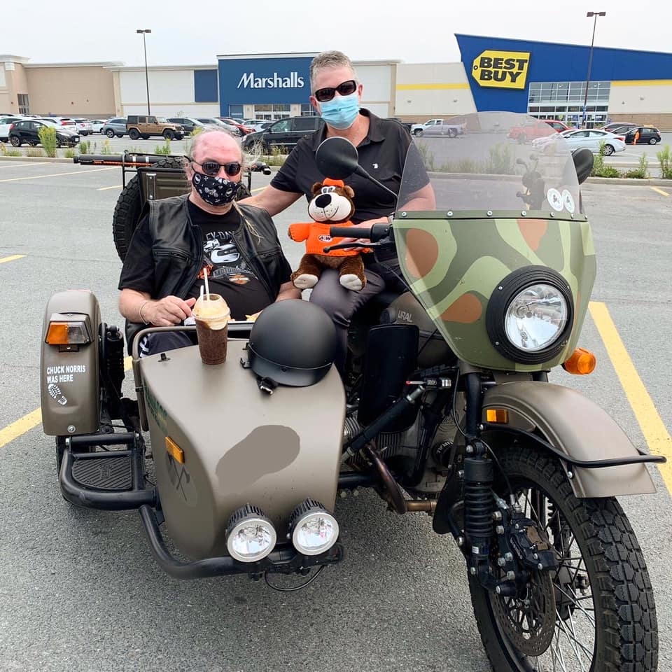 two people sitting in motorcycle with teddy bear