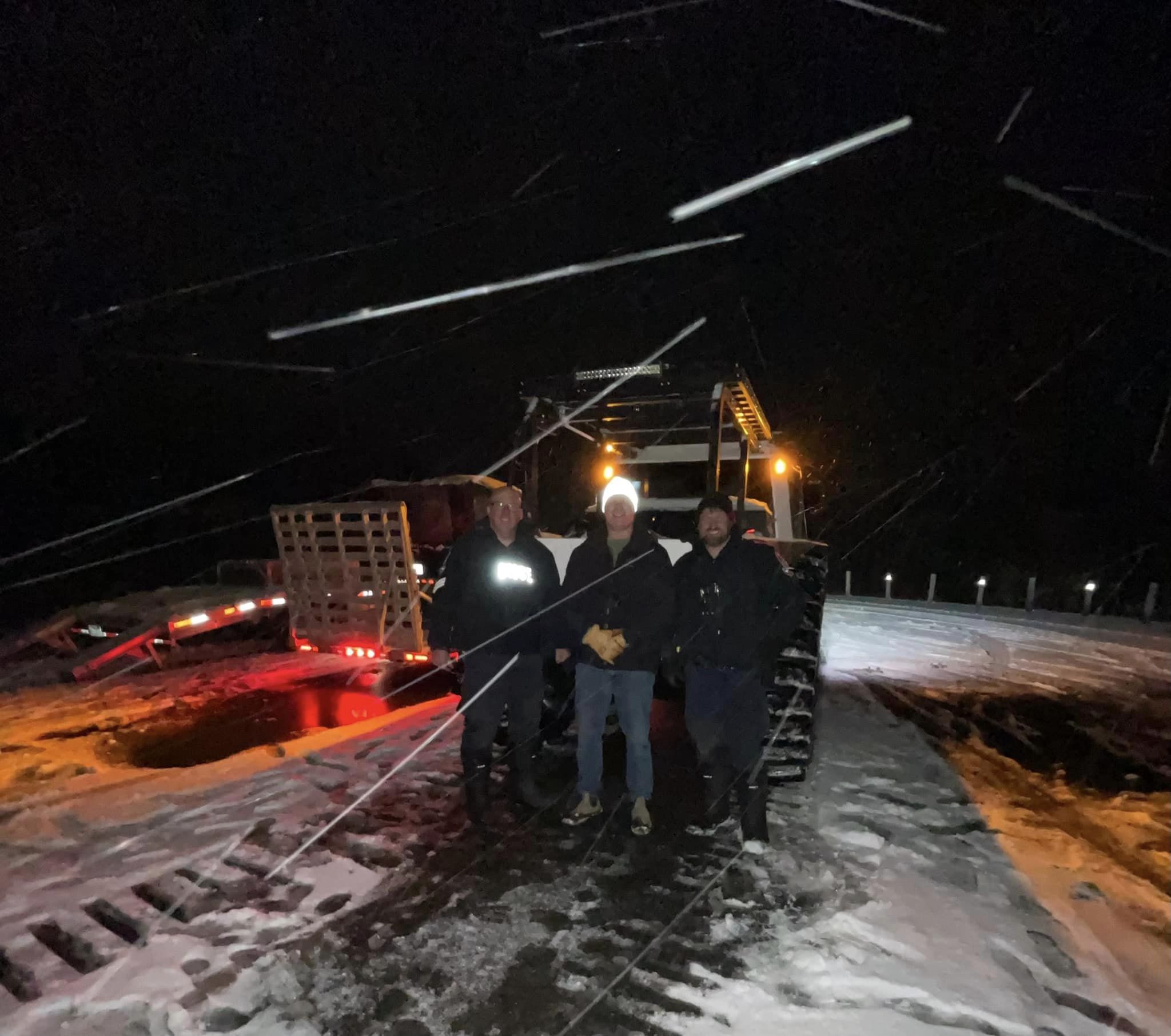 three men standing in front of fat truck in winter storm
