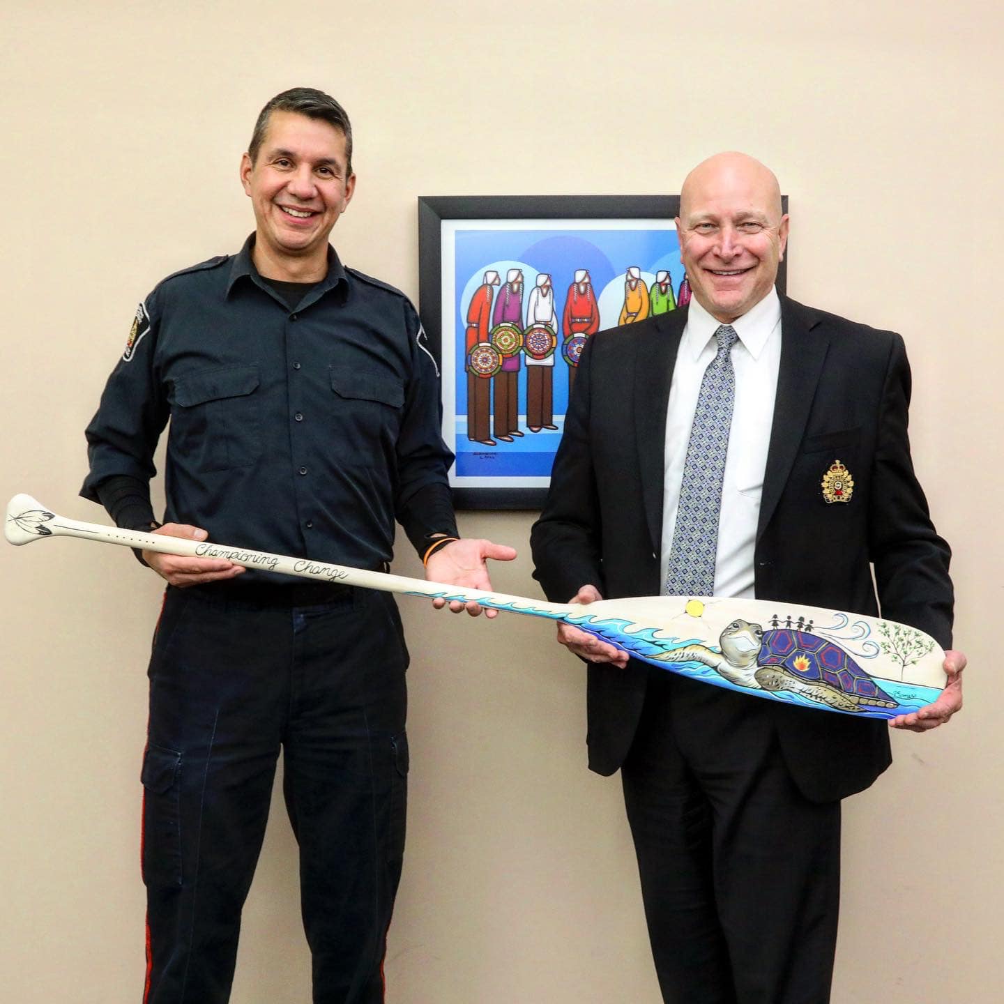 two men holding a painted paddle