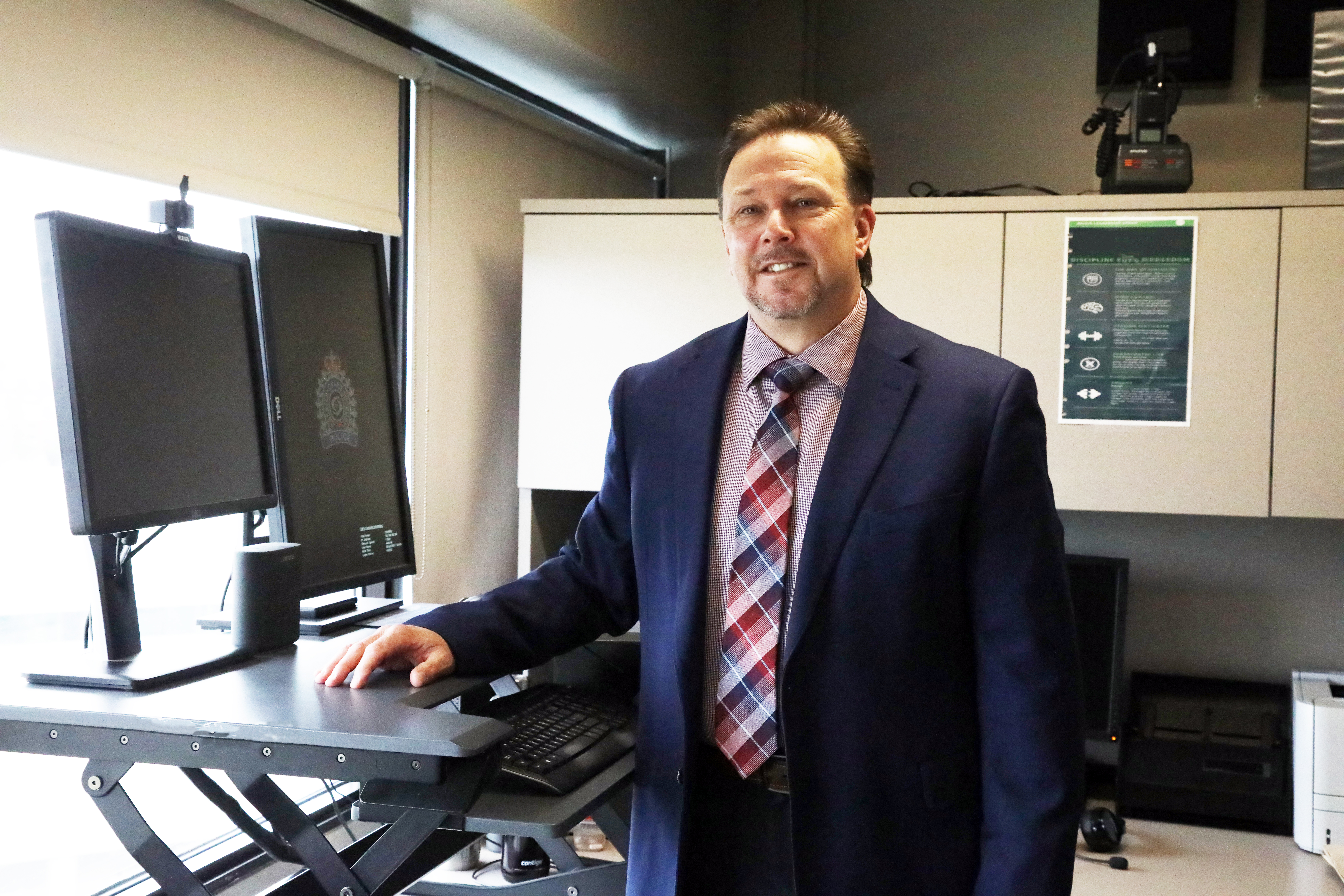 man in a suit standing beside computer