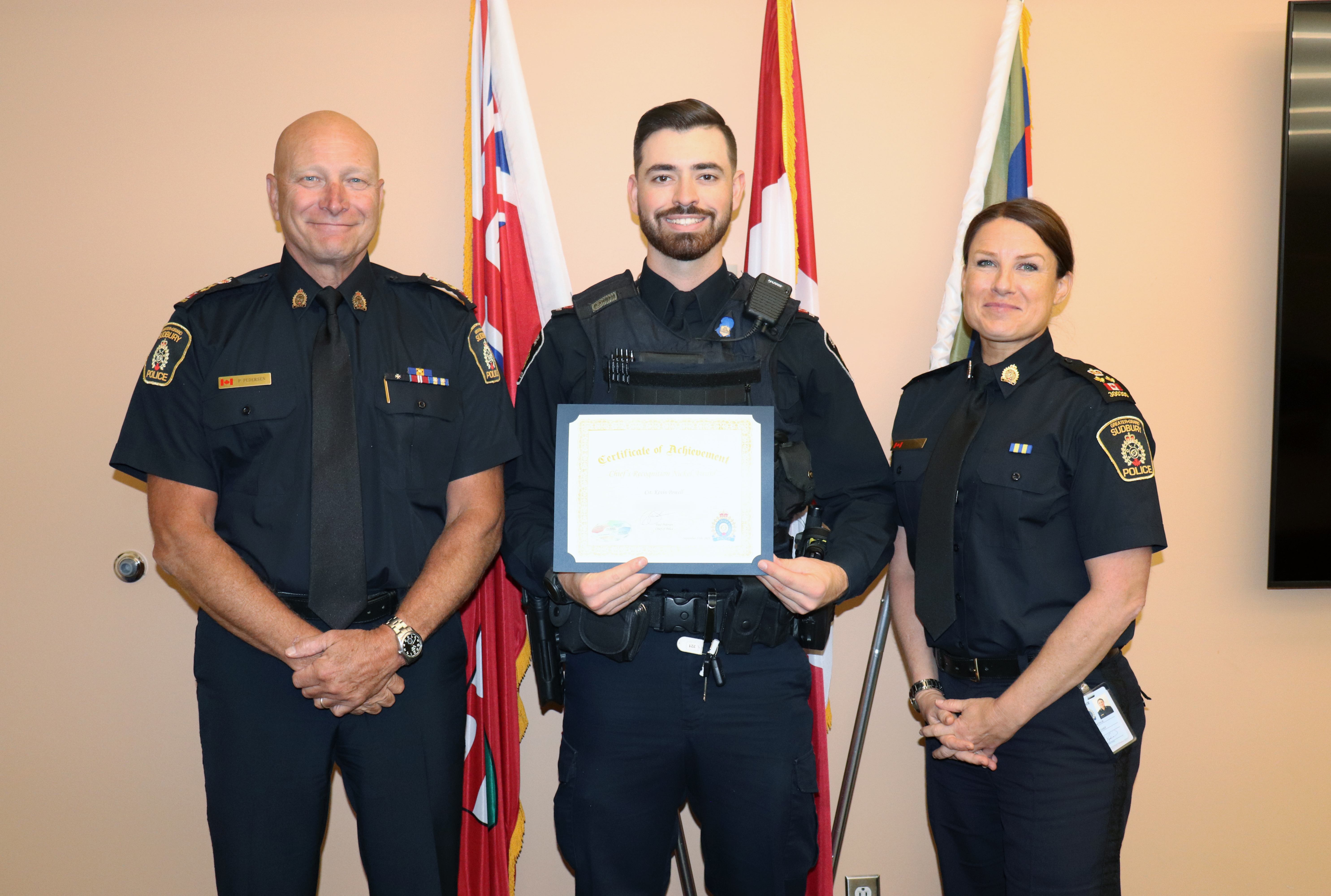 Three uniformed individuals smiling and holding certificate