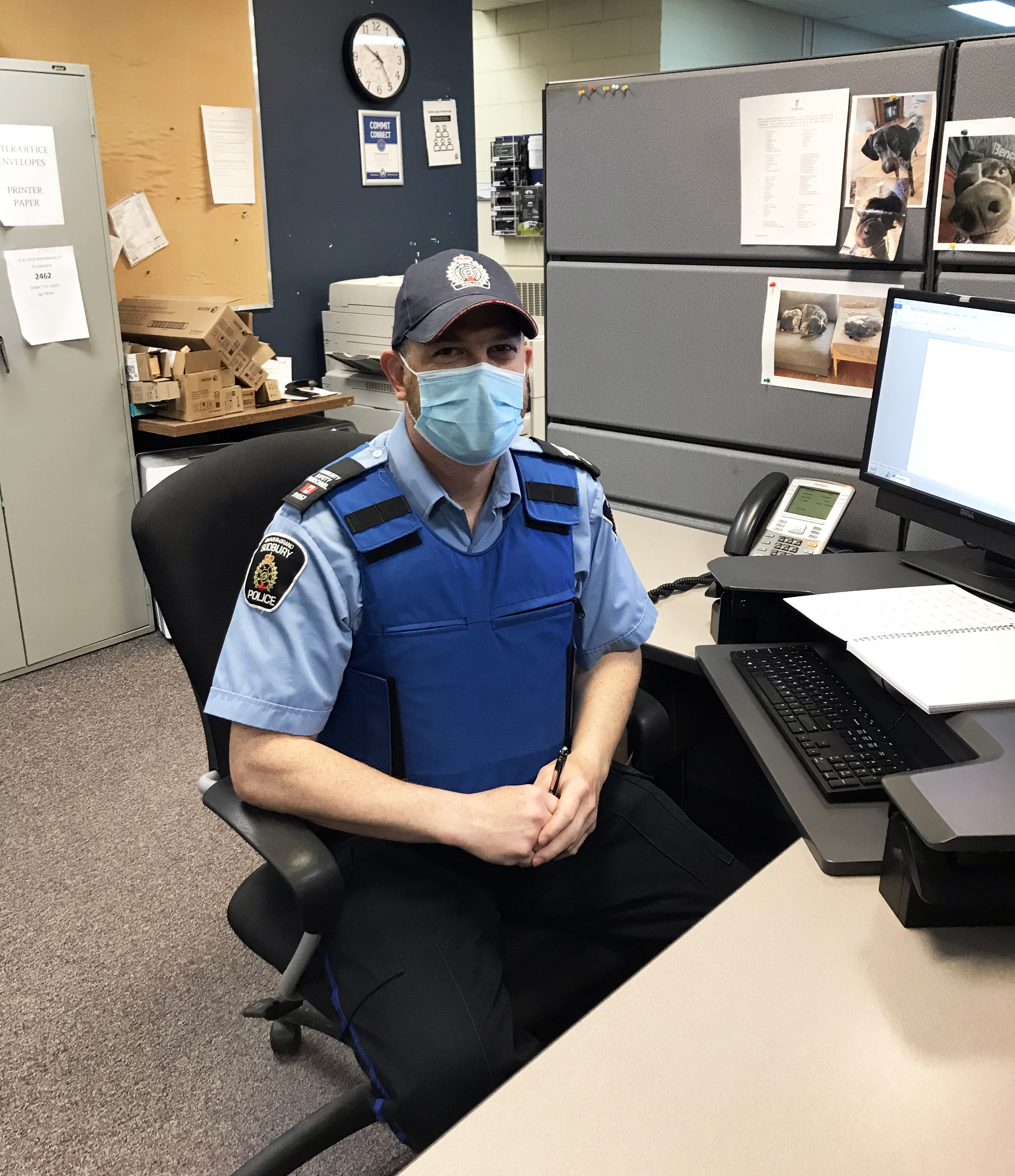 man in uniform sitting at desk with mask on