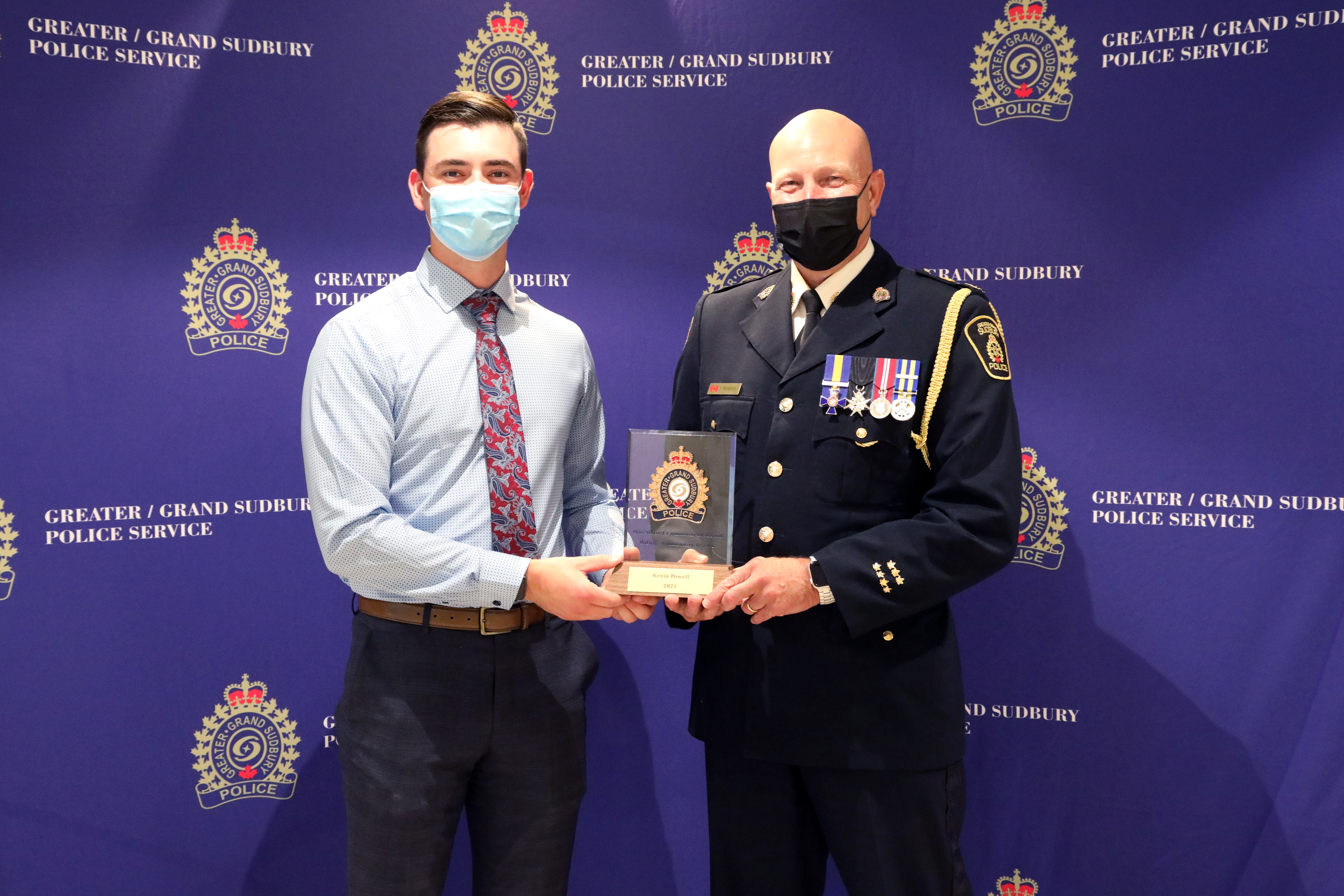 two men standing holding an award 