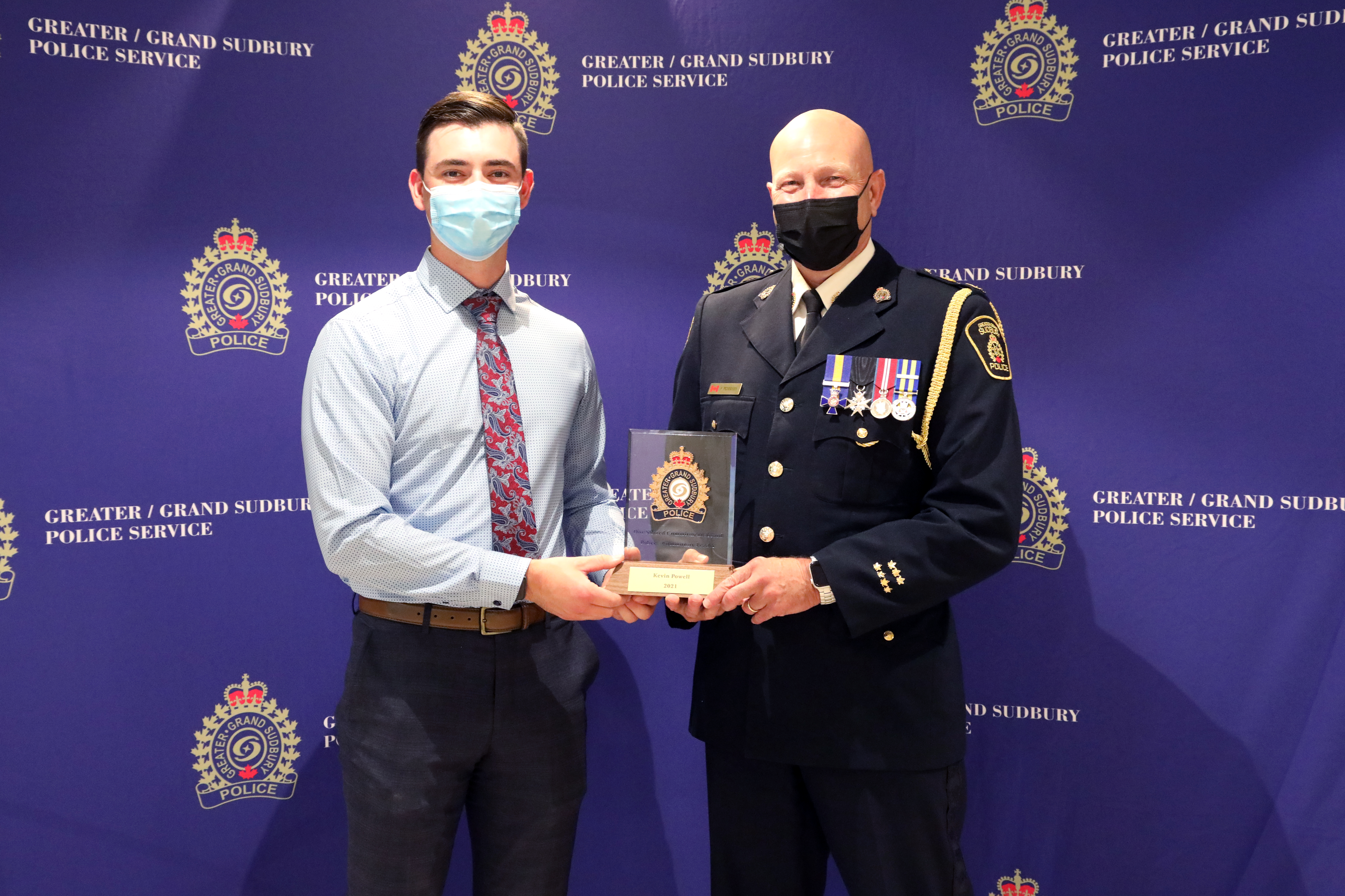 two men standing holding an award 