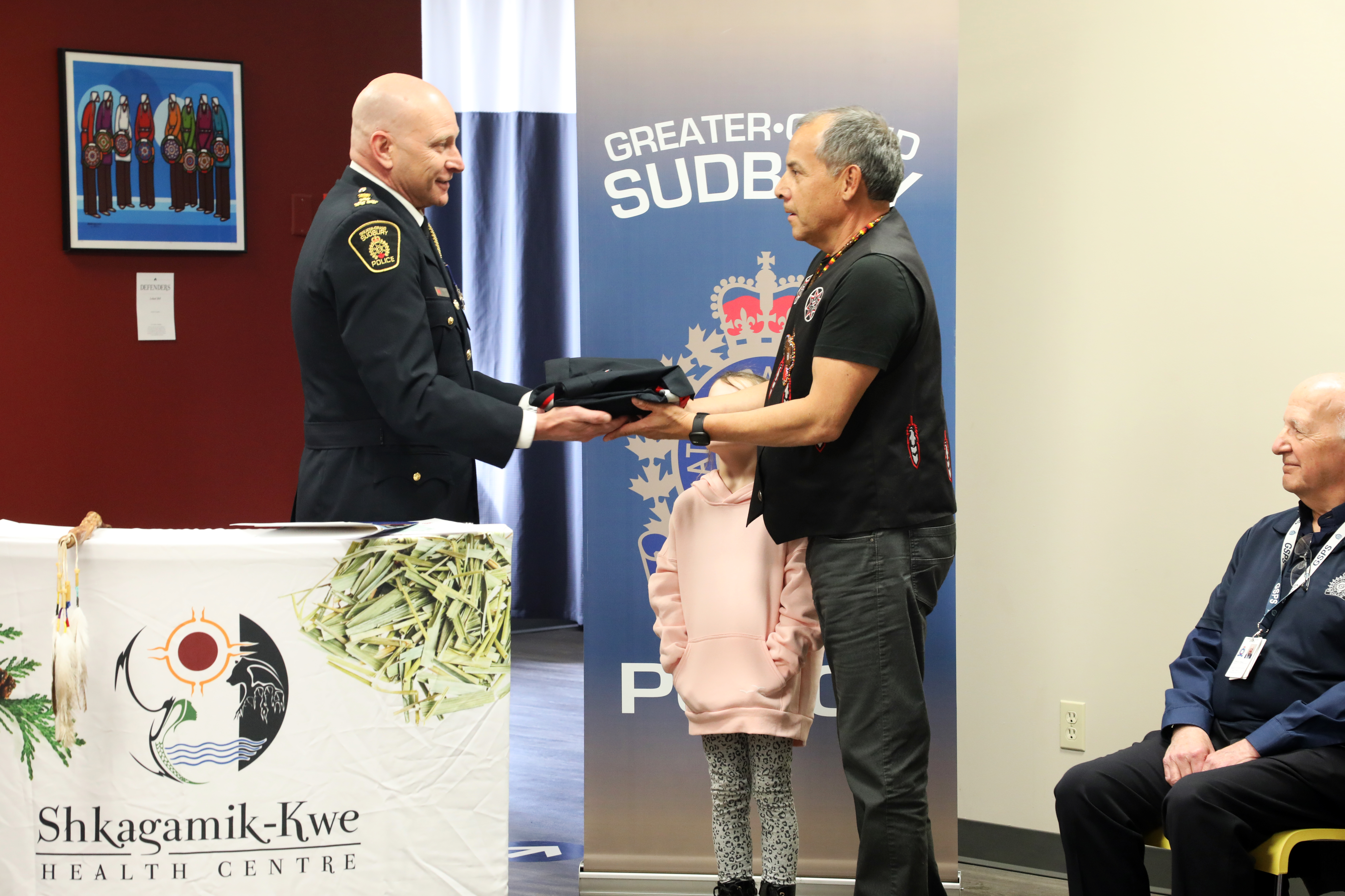 chief of police handing ribbon shirt to man