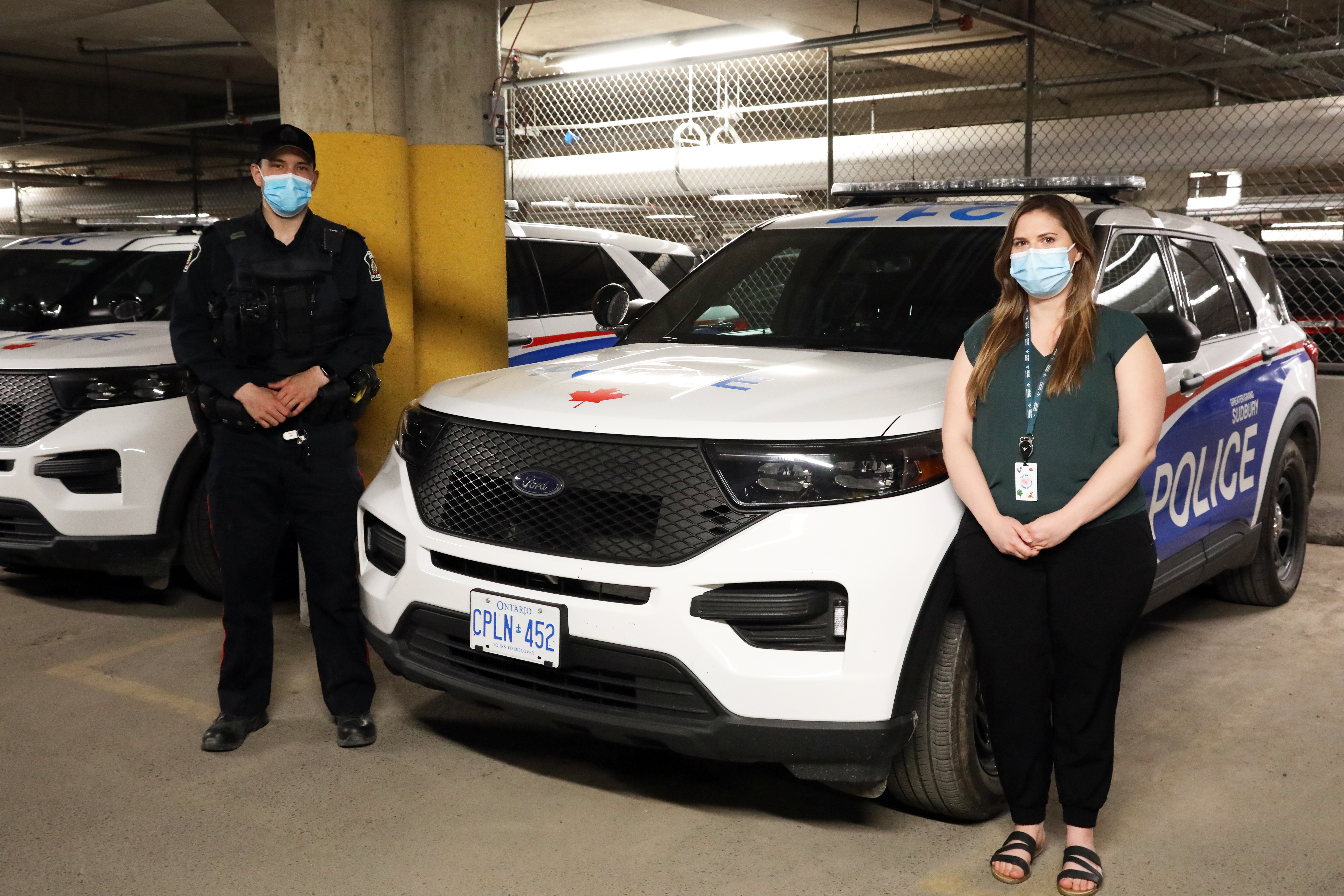 police officer and woman standing beside cruiser