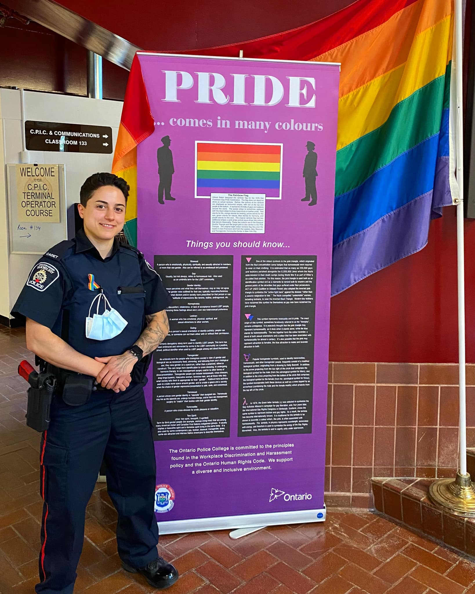person standing in front of pride flag and banner