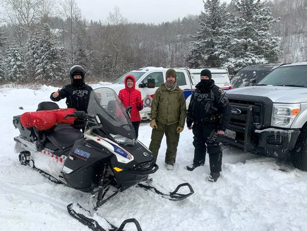 four people standing outside in the snow in the bush