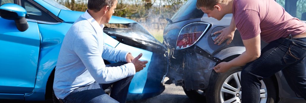 two people looking at car damage after collision