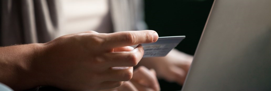 person holding credit card and using lap top