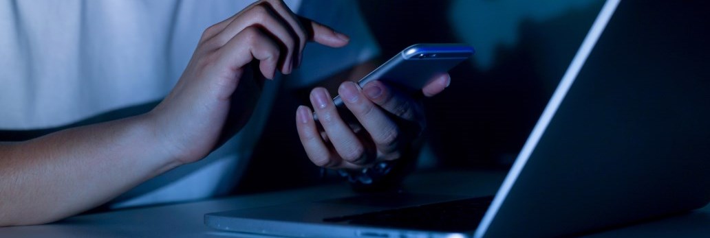 person holding cell phone and lap top