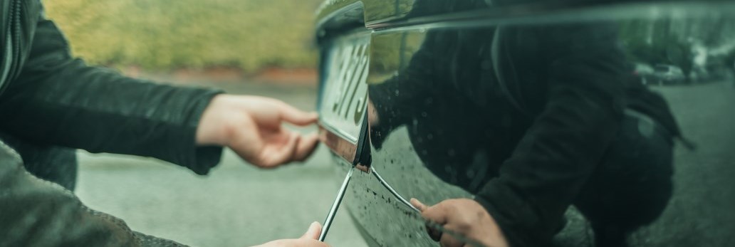 person removing licence plate from vehicle