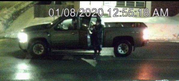 Grey or Silver pick up truck with woman in black jacket standing outside passenger door